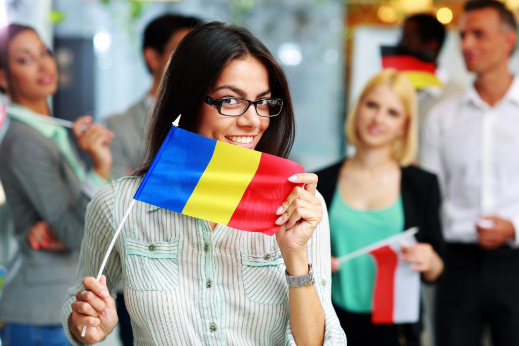 Happy businesswoman holding flag of Romania in front of colleagues